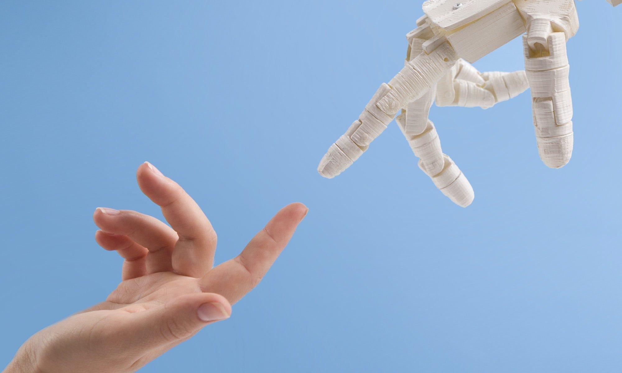 Female and robot hands reaching to each other on blue background